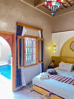 a bedroom with a bed and a window and a tub at Riad Dar Susan - Authentic Stay in Zagora in Zagora