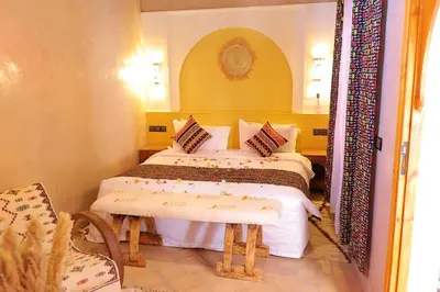 a bedroom with two beds and a table and a mirror at Riad Dar Susan - Authentic Stay in Zagora in Zagora