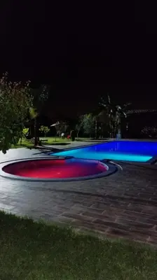 a lit up pool at night with blue and red at villa ezzaouak in Marrakech