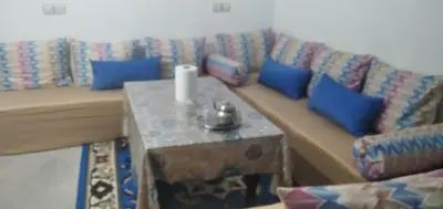 a couch with blue pillows and a table in a room at شقة في البادية الهدوء والطبيعة نواحي فاس مكناس in Fès