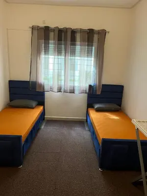 two beds in a room with a window at Appartement à marjane in Meknès