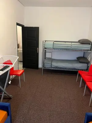 a room with two bunk beds and red chairs at Appartement à marjane in Meknès