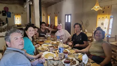 a group of people sitting around a table eating food at kasbah luna del sur in Erfoud