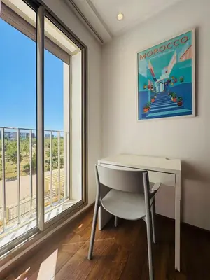 a table and a chair in a room with windows at Paradise Prestigia Fes City Center sur Parc in Fès