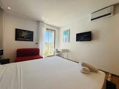 a bedroom with a white bed and a red chair at Paradise Prestigia Fes City Center sur Parc in Fès