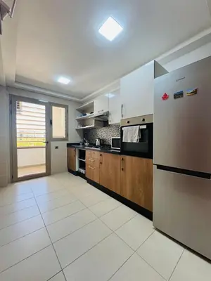 a large kitchen with a refrigerator and wooden cabinets at Paradise Prestigia Fes City Center sur Parc in Fès
