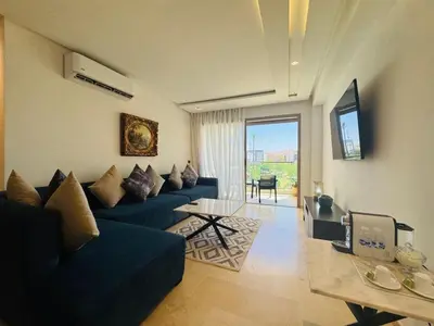 a living room with a blue couch and a table at Paradise Prestigia Fes City Center sur Parc in Fès