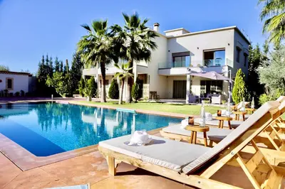 a villa with a swimming pool and a house at *Villa de luxe à Marrakech, vue sur les montagnes* in Marrakech