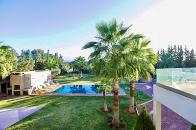 an image of a villa with a swimming pool and palm trees at *Villa de luxe à Marrakech, vue sur les montagnes* in Marrakech