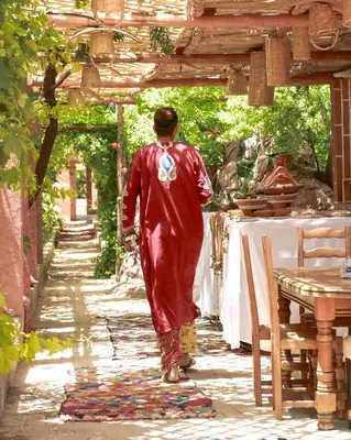 a person in a red robe walking down an alley at Ecolodge Aroma Dades in El Hart