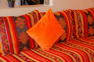 an orange pillow sitting on top of a colorful couch at Wadahab House An Ideal Retreat for Families and Friends in Er Rachidia