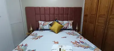 a bed with a red headboard and pillows on it at Fes Panoramic Luxury Apartments in Fès