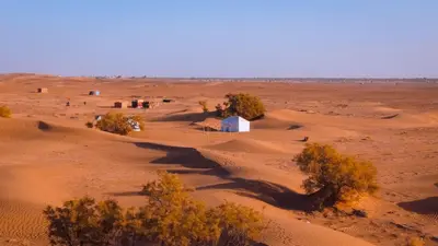 a desert with a small white building in the middle at Trek Plan Camp in Mhamid
