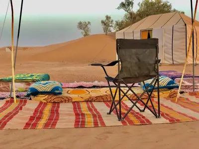 a chair sitting on a rug in the desert at Trek Plan Camp in Mhamid