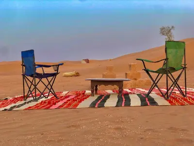 two chairs and a table in the desert at Trek Plan Camp in Mhamid