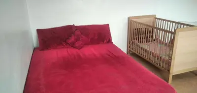 a bed with a red blanket next to a crib at Familles avec bébé in Fès