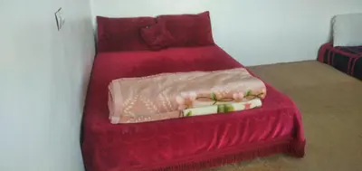 a red bed with a red bedspread on it at Familles avec bébé in Fès