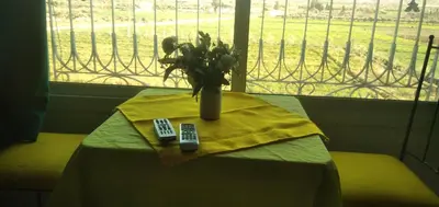 a table with a vase of flowers and two remote controls at Familles avec bébé in Fès
