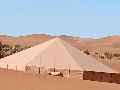 a tent in the desert with mountains in the background at Stay under millions of stars deep in the desert in El Gouera