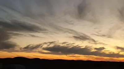 a cloudy sky at sunset with mountains in the background at Stay under millions of stars deep in the desert in El Gouera