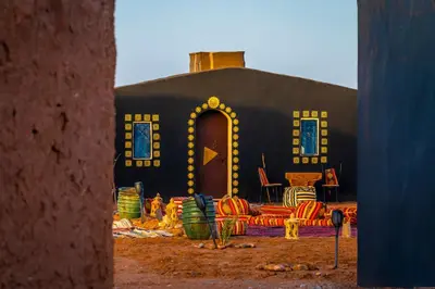 a black building with a table and chairs in front of it at Mhamid Nomad Camp in Mhamid