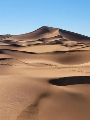 a sand dune in the desert with a blue sky at Mhamid Nomad Camp in Mhamid