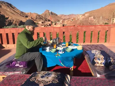 a man sitting at a table with a blue table cloth at Gorges View Dades in Tamellalt