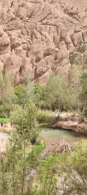 a person standing next to a body of water next to a mountain at Gorges View Dades in Tamellalt