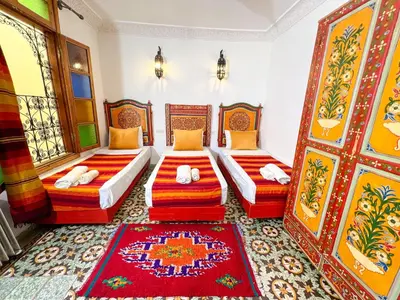 two beds in a room with red and orange at Dar Houda in Fès