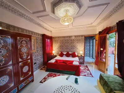 a bedroom with a red bed and a chandelier at Hôtel&Restaurant Villa des étoiles in Ourika