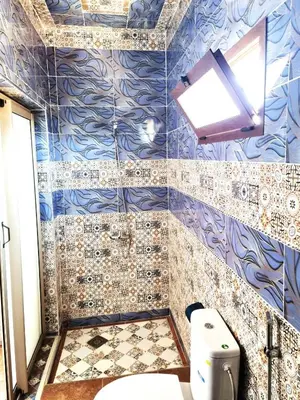 a bathroom with a toilet and a blue tiled wall at Hôtel&Restaurant Villa des étoiles in Ourika