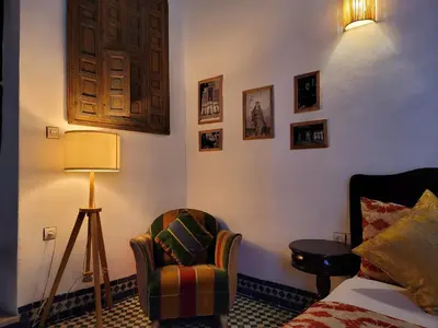 a room with a bed and a chair and a lamp at Youssef in Fès