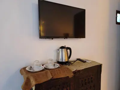 a tv on a wall with a table with a tea kettle at Youssef in Fès