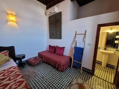 a room with a bed and a chair and a sink at Youssef in Fès