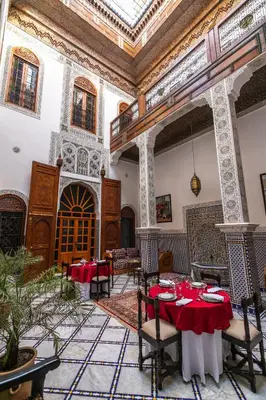 a dining room with a table and chairs and a ceiling at Riad Jamal in Fès