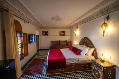 a bedroom with a large bed with a red blanket at Riad Jamal in Fès