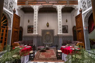 a dining room with red tables and a fireplace at Riad Jamal in Fès