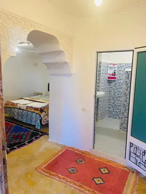 a room with a bathroom with a shower and a red rug at Riad et Restaurant chez Alilouch in Nkob