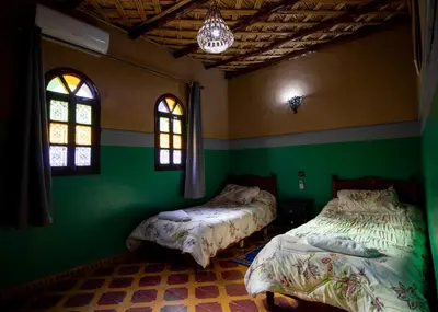 two beds in a room with green walls and windows at Palma Ziz in Aït Athmane