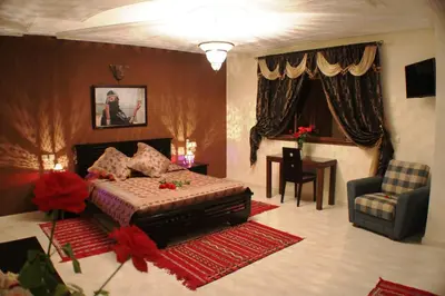 a bedroom with a bed and a couch and a chair at Riad Mimosa in Fès