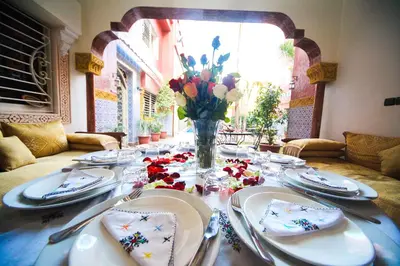 a table with plates and a vase of flowers on it at Riad Mimosa in Fès