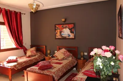 a room with two beds and a vase of flowers at Riad Mimosa in Fès