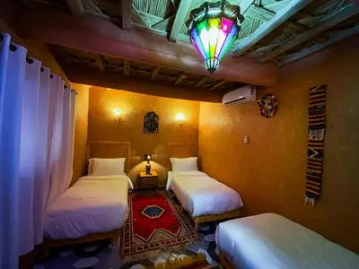 a room with three beds and a chandelier at Riad Tamdakhte in Aït Ben Haddou