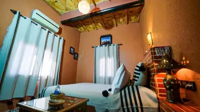 a bedroom with a bed and a table and a chair at Riad Tamdakhte in Aït Ben Haddou