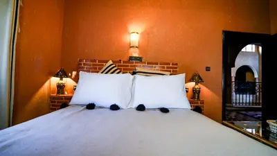 a bedroom with a white bed with two pillows at Riad Tamdakhte in Aït Ben Haddou