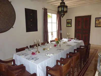 a dining room with a long table and chairs at Exceptionnelle Villa riad avec cuisinière-Piscine chauffée-Fibre internet in Marrakech