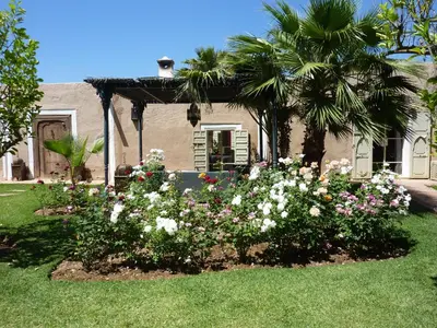 a garden of flowers in front of a house at Exceptionnelle Villa riad avec cuisinière-Piscine chauffée-Fibre internet in Marrakech