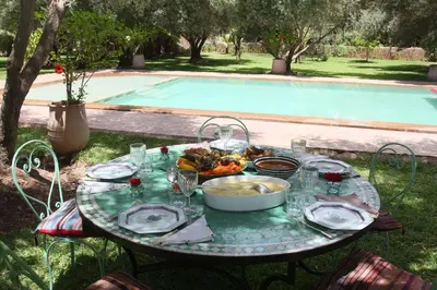 a table with a plate of food next to a pool at Exceptionnelle Villa riad avec cuisinière-Piscine chauffée-Fibre internet in Marrakech