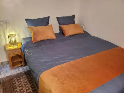 a bedroom with a large bed with orange and blue pillows at Riad Averroès in Fès