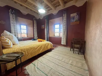 a bedroom with a bed and a table and chairs at KASBAH ALTAÏR in Kalaat MGouna
